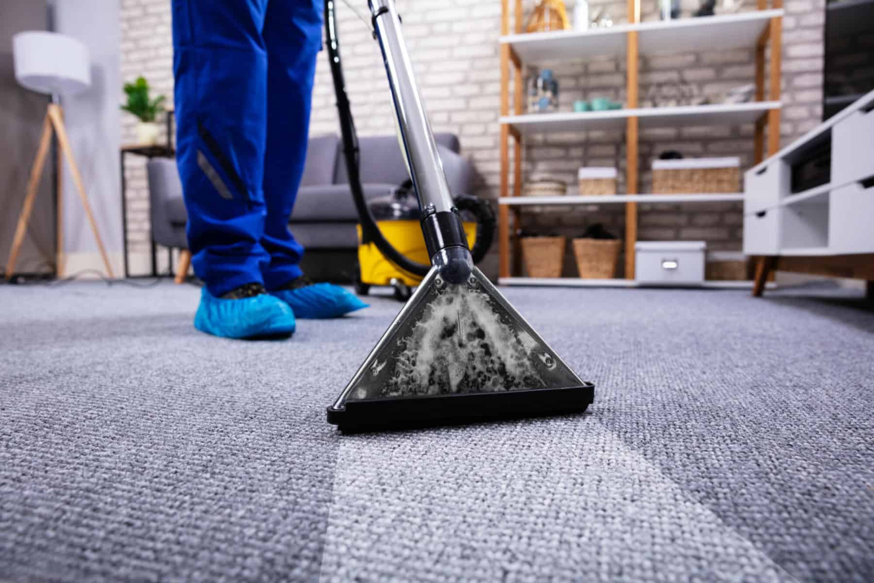 A man cleaning carpet using a vacuum cleaner